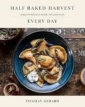 Blue ceramic bowl filled with savory dumplings garnished with sage and creamy sauce from half baked harvest every day