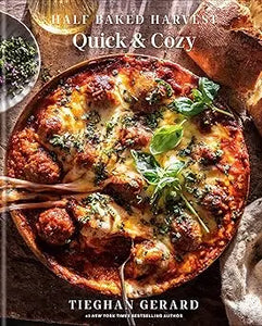 A rustic wooden spoon rests in a golden-brown cheesy meatball pizza with fresh basil from half baked harvest quick cozy