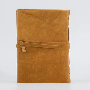 Tan suede-bound leather journal for women and men with a matching leather strap tied around the cover