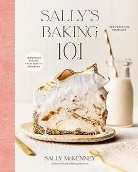 A slice of meringue-topped pie with golden caramelized edges on a white plate on the cover of Sallys Baking 101
