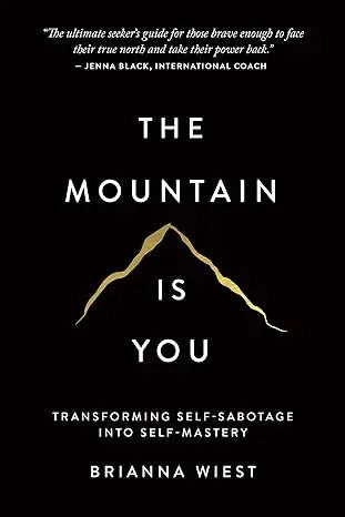 Black hardcover book the mountain is you by brianna wiest with gold foil title and mountain design on cover