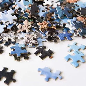 Scattered blue and black jigsaw puzzle pieces showing moraine lake landscape from yundu 1000 piece puzzles for adults
